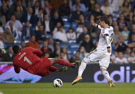 Malaga's goalkeeper Carlos Kameni dives for the ball at the feet of Real Madrid's Cristiano Ronaldo on May 8, 2013